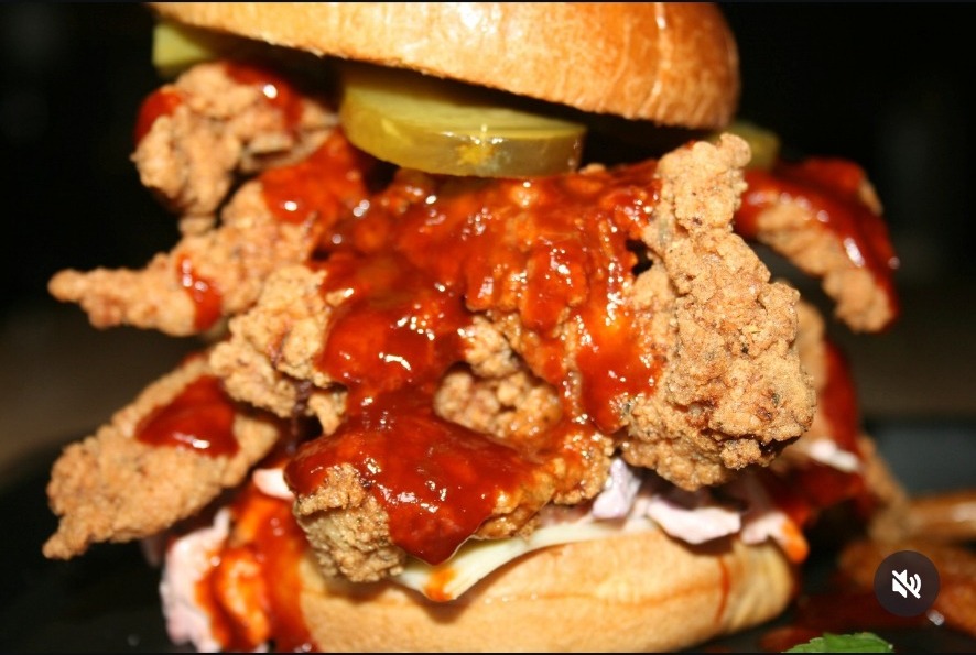 Signature stack burger with sauce running over crispy chicken
