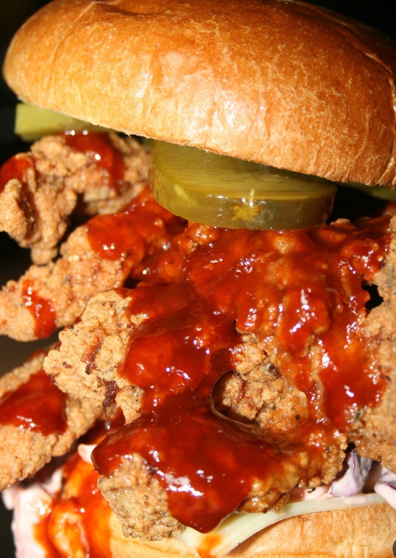 Signature stack burger covered in sauce with crispy chicken and pickles